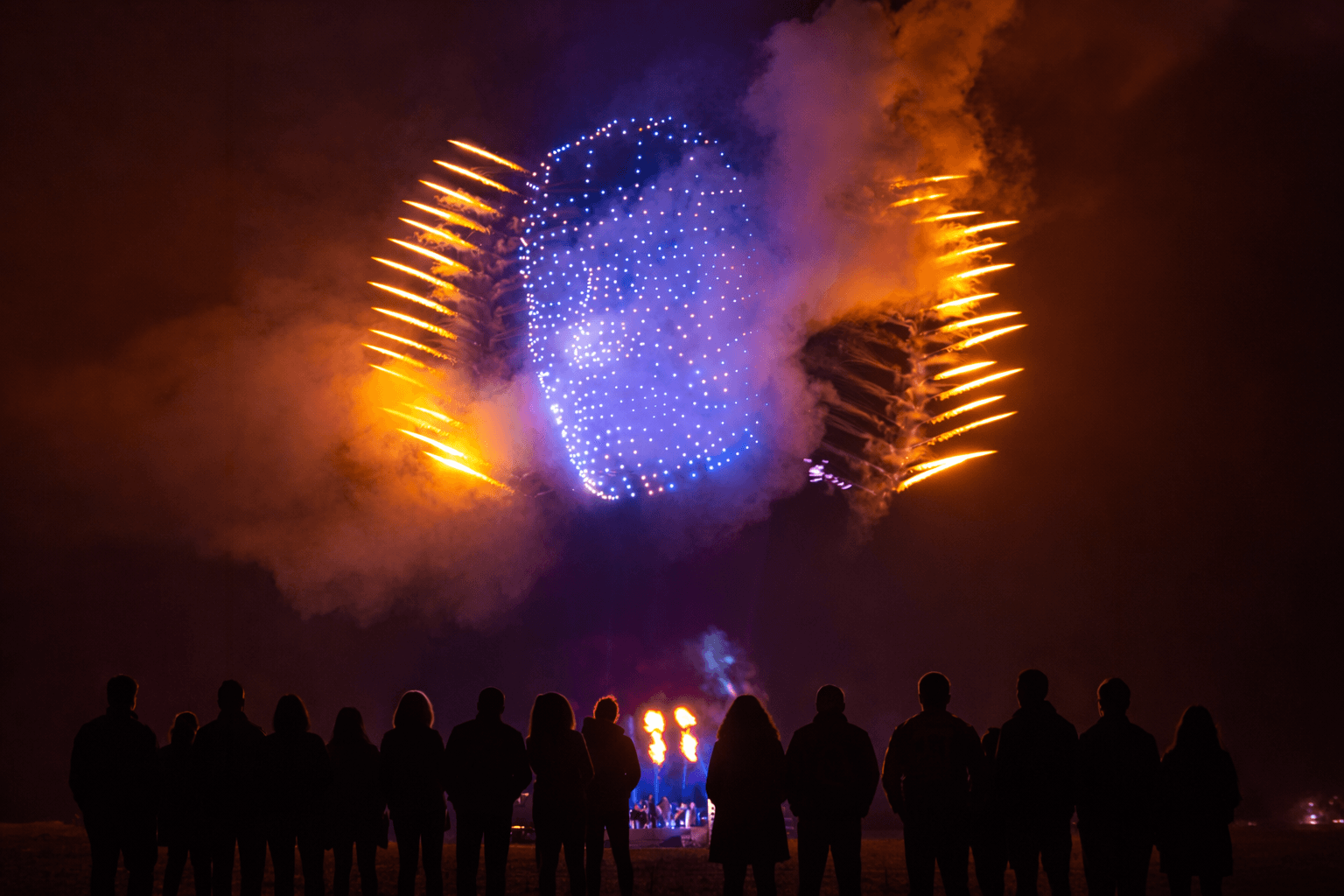 MD6 fleet forming a luminous sphere with pyrotechnics over a crowd