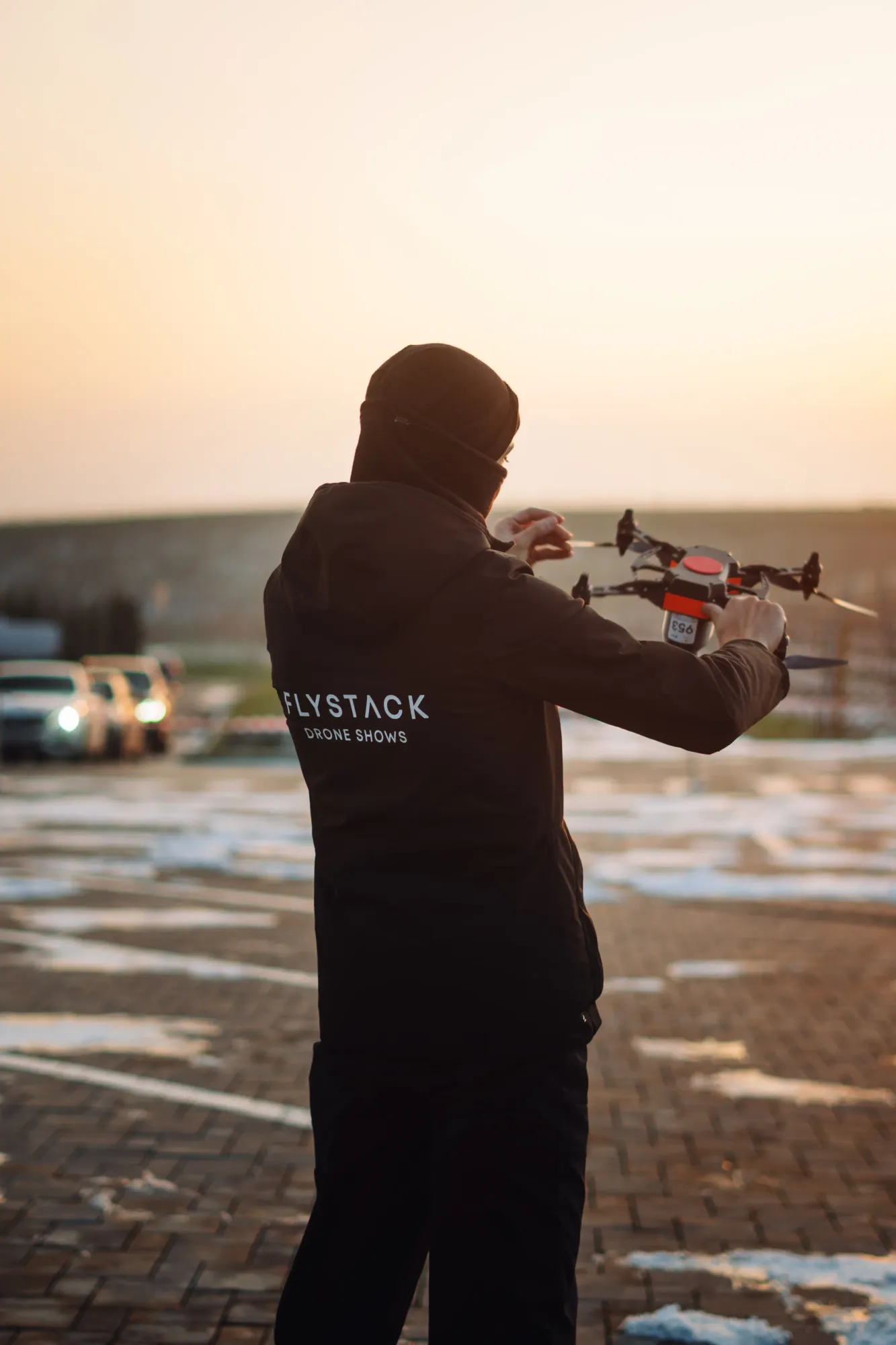 A FLYSTACK operator preparing a drone for launch at sunset before a show