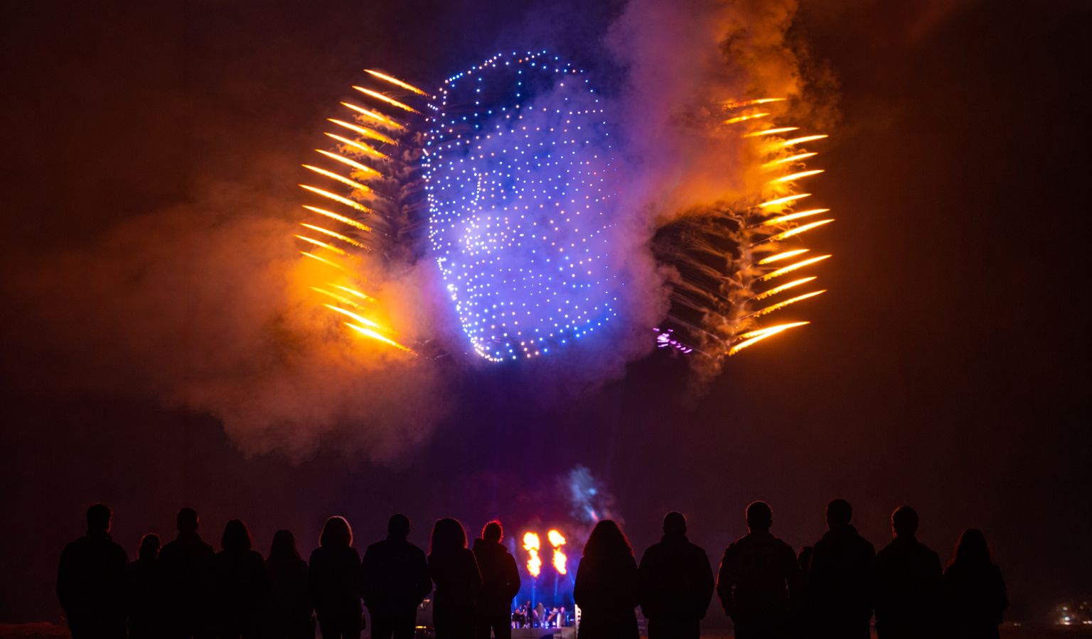 MD6 fleet forming a luminous sphere with pyrotechnics over a crowd